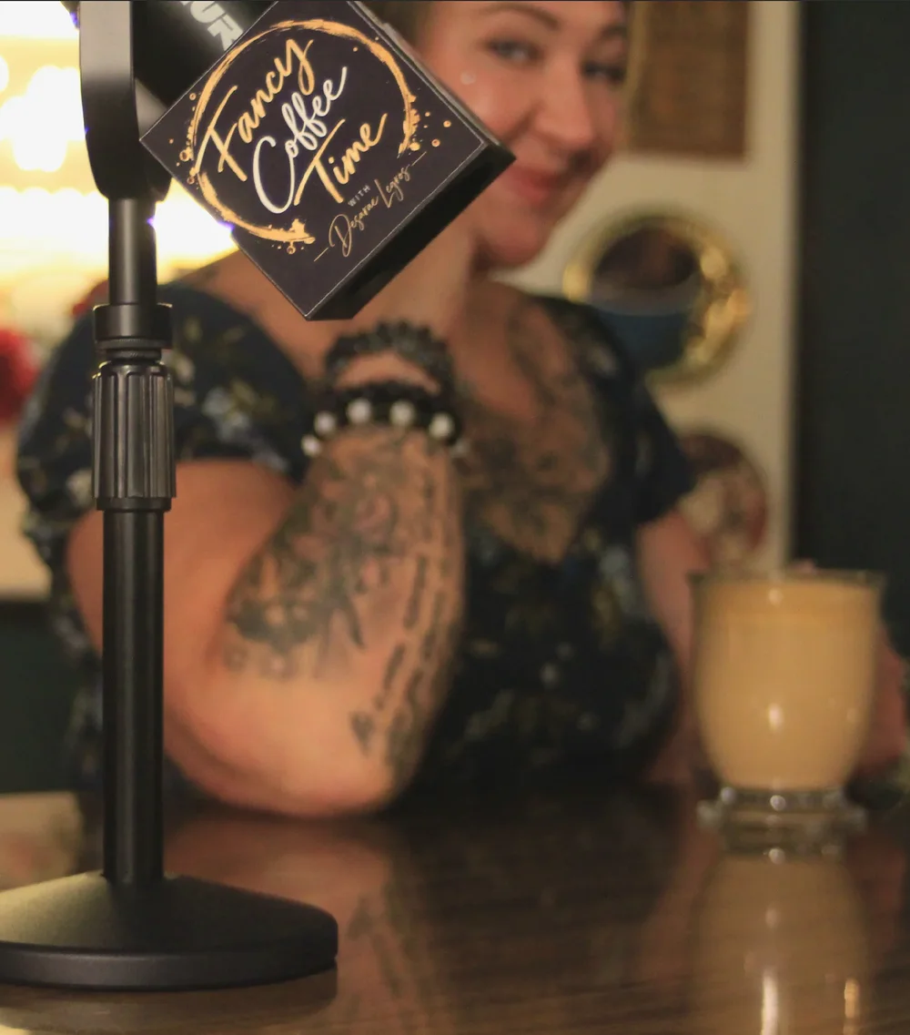 Desarae behind a Fancy Coffee Time microphone with a coffee