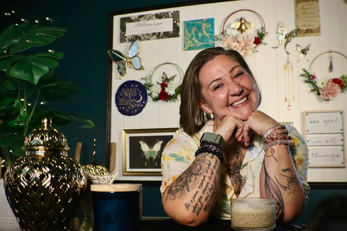 Desarae smiling at a table in her warmly decorated studio